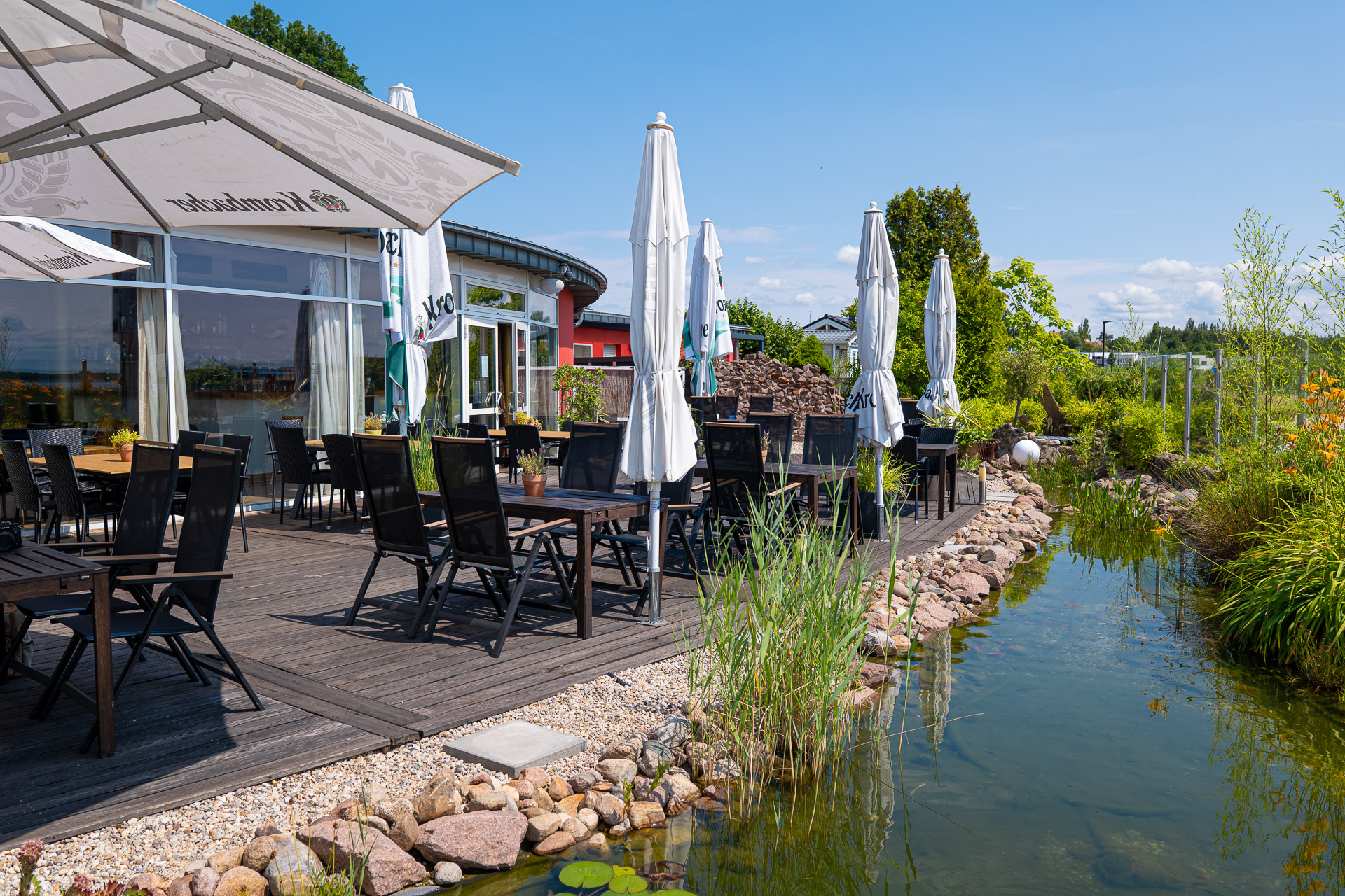 Außenbereich der Bernstein Events Location am Goitzschesee mit Terrassenmöbeln und Sonnenschirmen