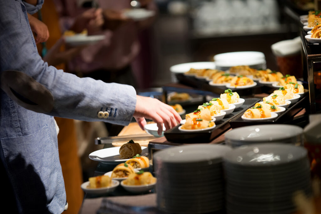 Person steht an einem hochwertigen Fingerfoodbuffet und greift nach einer kleinen Schale.