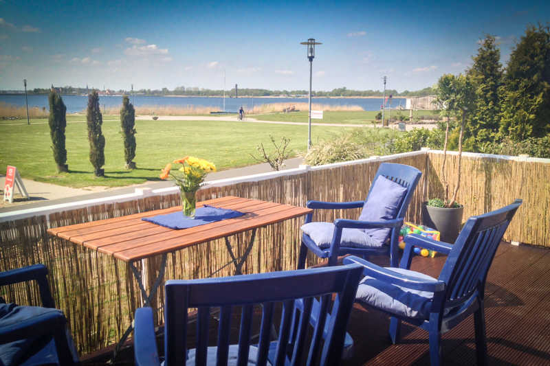 Terrasse mit blauen Sitzmöbeln und Ausblick auf den Goitzschesee
