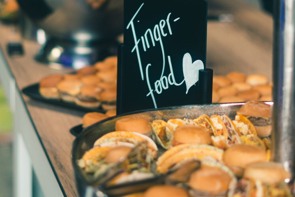 kleine Burger auf Platten, daneben ein Schild mit der Aufschrift "Fingerfood"