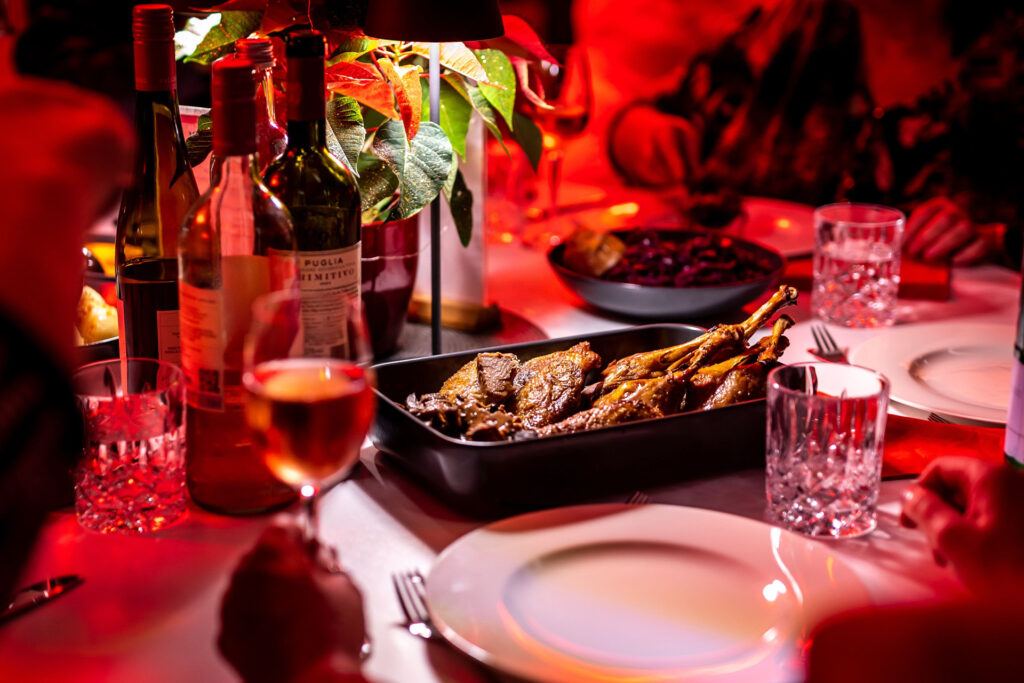 weihnachtlicher Dinnertisch mit Platten voll Entenbrust und Rotkohl, gefüllten Wein- und Wassergläsern