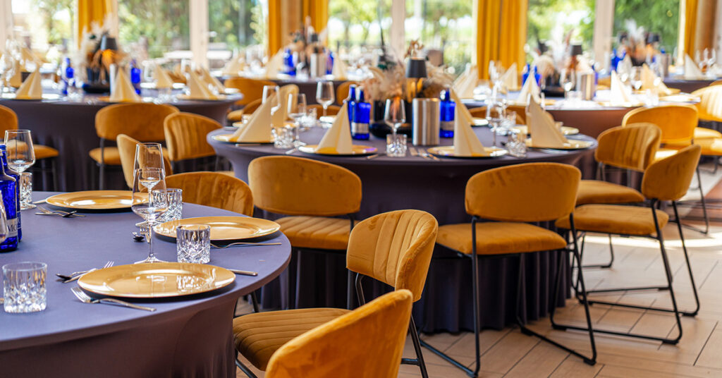 Veranstaltungsraum der Bernstein Events Location am Goitzschesee mit goldenen Stühlen und runden Tischen