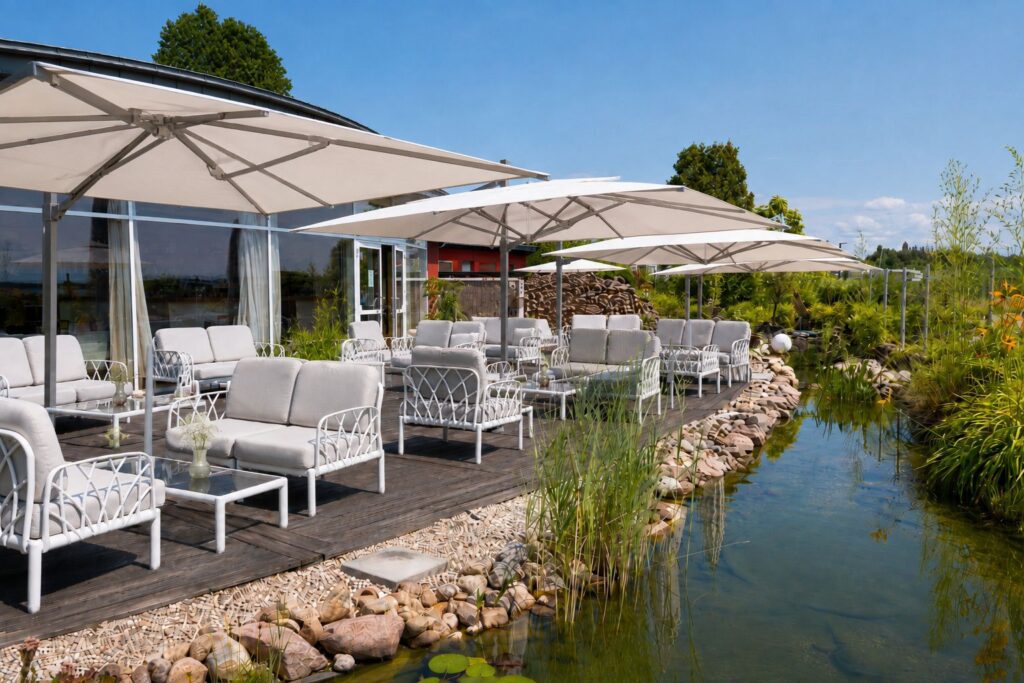Terrasse des BERNSTEIN mit weißen Loungemöbeln, aufgespannten Schirmen und kleinem Bachlauf