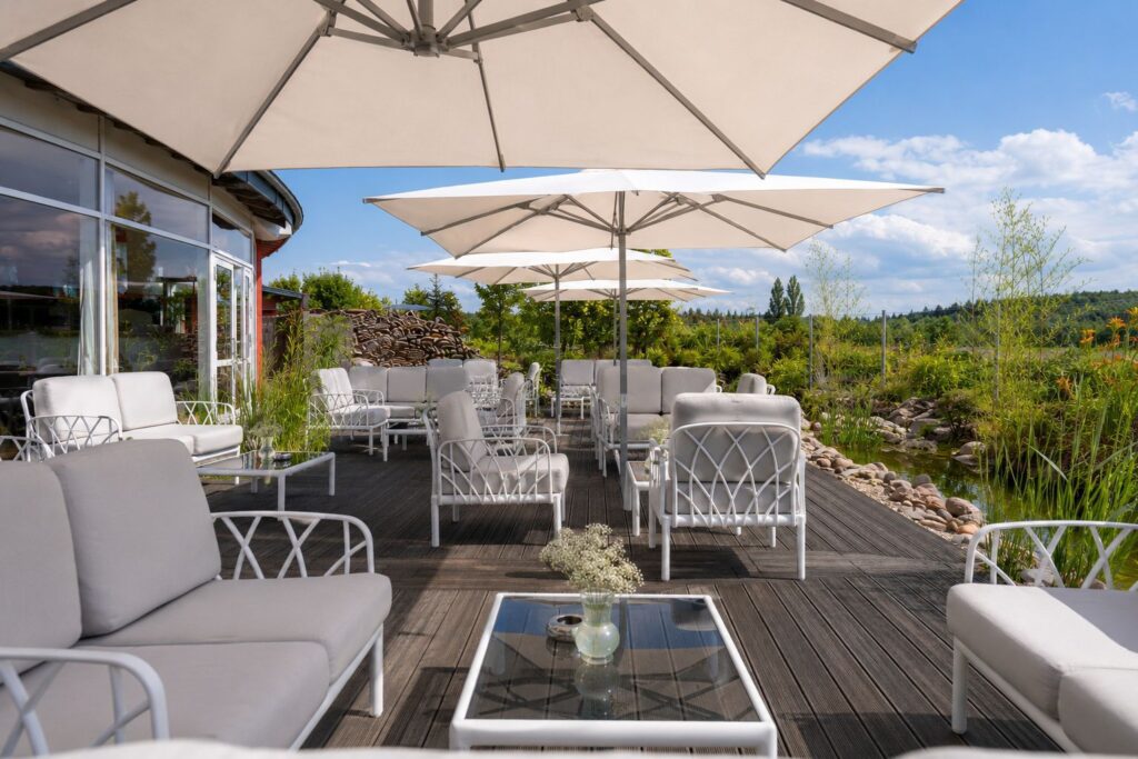Terrasse des BERNSTEIN mit weißen Loungemöbeln und aufgspannten Schirmen bei Tag